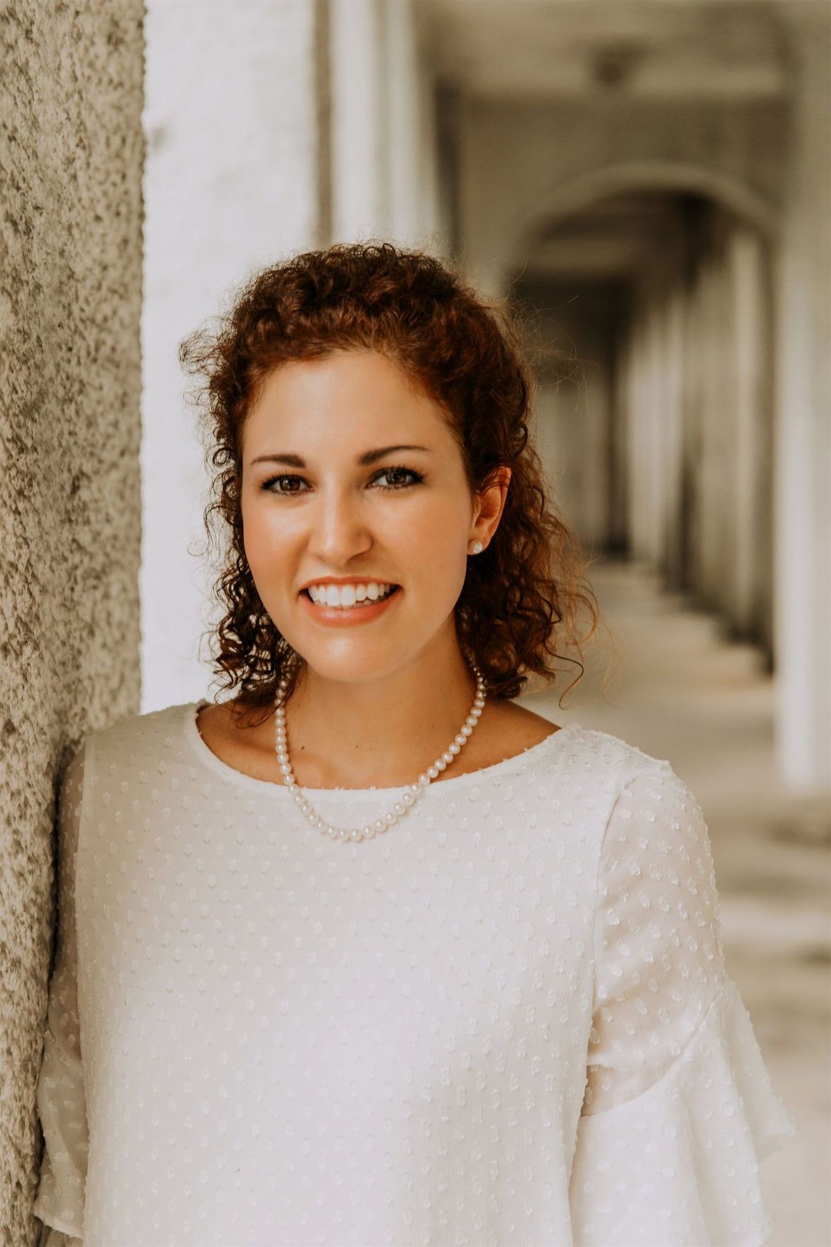 Kara Klein Oubre in a white shirt headshot by a white pillar version one