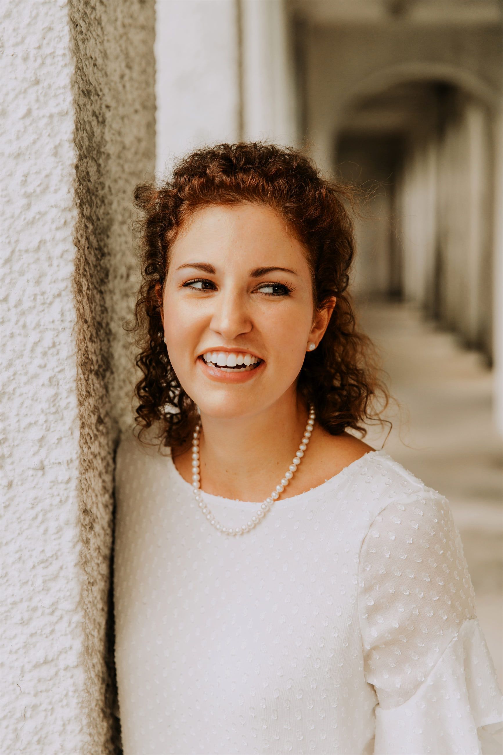 Kara Klein Oubre in a white shirt headshot by a white pillar version two
