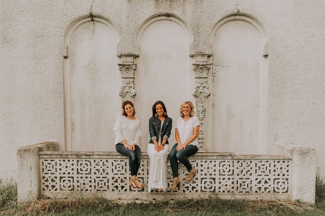 Kara Klein Oubre, Christine Simpson Wessa, and Maria Spears in front of a white stone background sitting