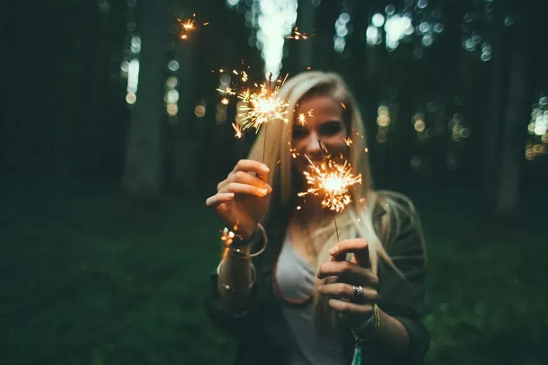 Women using sparklers in front of a camera